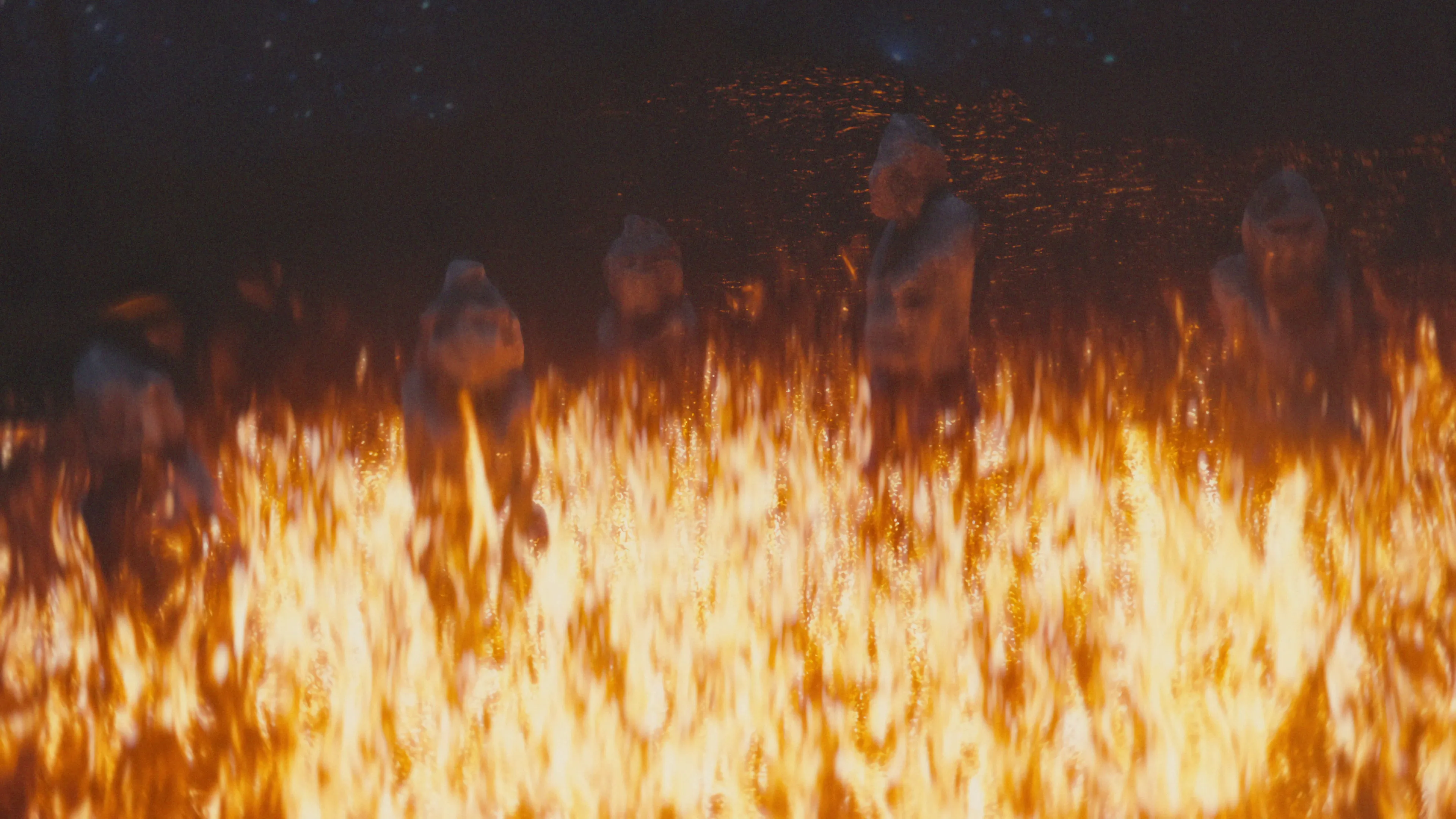 Dramatic CGI scene with ancient stone figures silhouetted against a raging wall of fire, showcasing high-end visual effects and intense cinematic lighting.