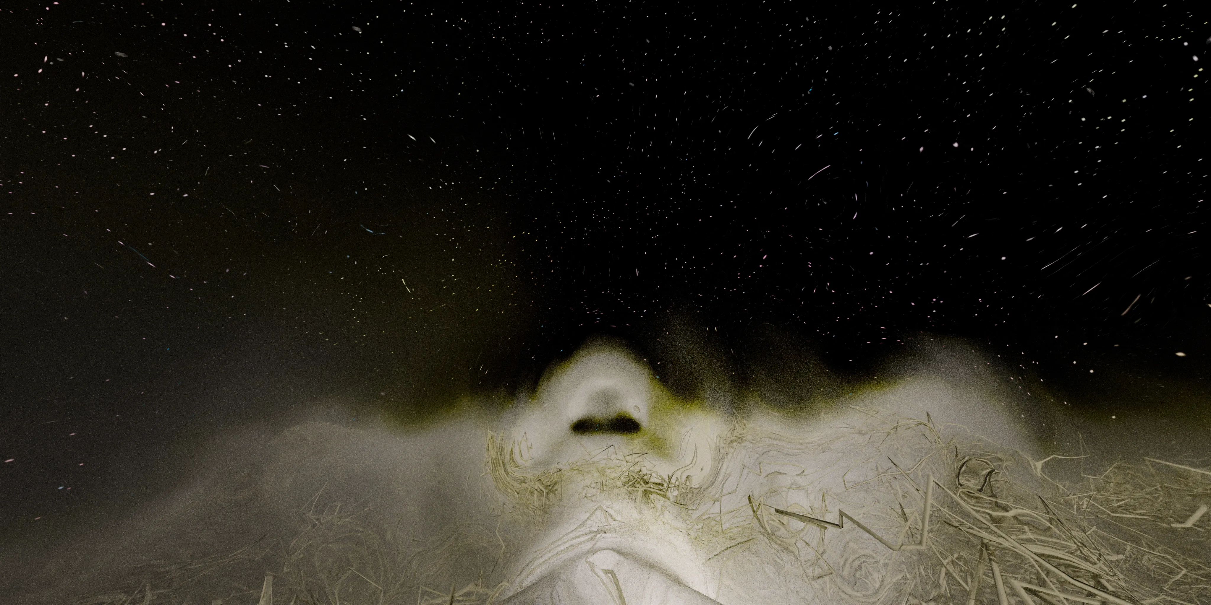 Atmospheric CGI vista of alien terrain beneath swirling star-filled sky, combining vast cinematic scale with experimental sci-fi environment design.